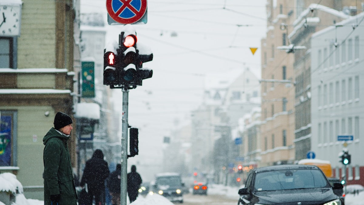 a man standing next to a traffic light in the snow