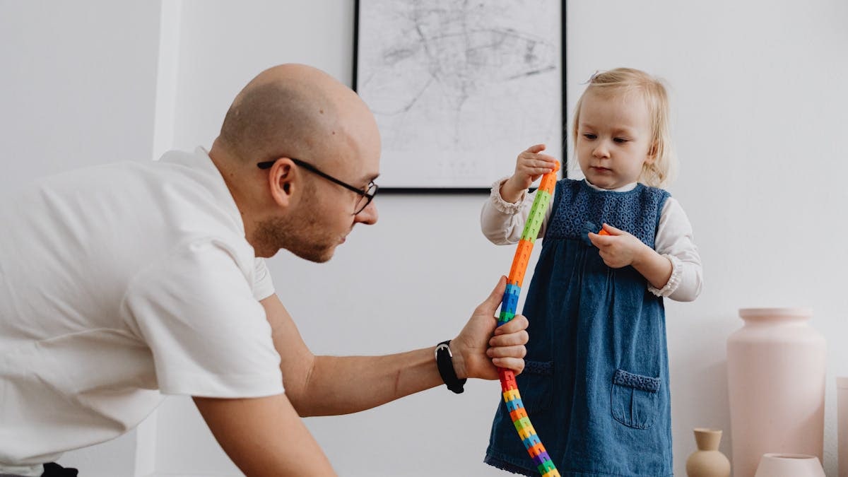 Father and daughter playing together with building blocks indoors, enhancing bonding and creativity.